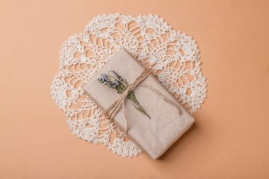 Noel ve sıfır ziyan, Kraft kağıdına sarılı çevre dostu hediye, bej arka planda örülmüş peçeteye kurutulmuş ardıç filizi. Eko dekorlu ekolojik tatil konsepti. Üst görünüm.