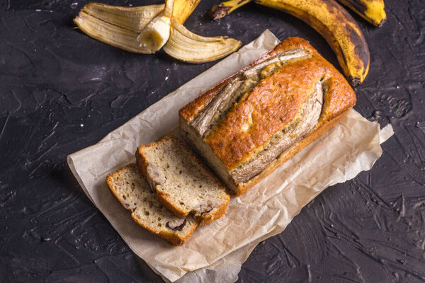 Традиционным американским блюдом является безглютеновый и молочный банановый хлеб на черном бетонном фоне. Вид сверху, пространство для копирования