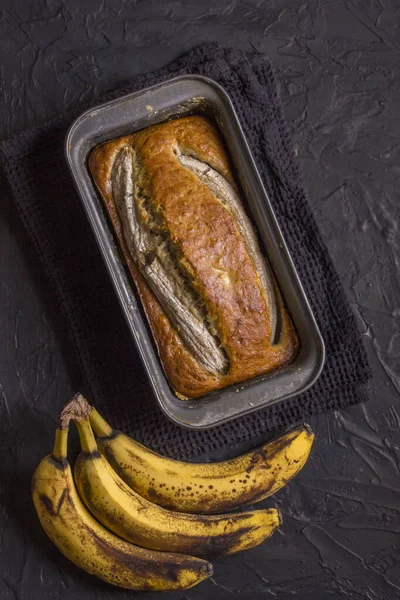 A traditional American dish is gluten and dairy free banana bread on a black concrete background. Top view, copy space