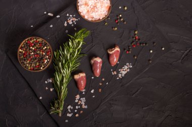 Kara tahtada taze çiğ tavuk kalbi, biber, tuz ve biberiye. Tavuk sakatatı. Üst görünüm, alanı kopyala