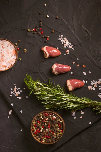 Kara tahtada taze çiğ tavuk kalbi, biber, tuz ve biberiye. Tavuk sakatatı