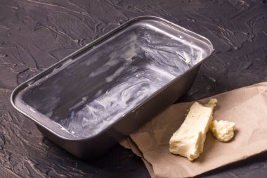 Tereyağlı ve dokulu siyah arkaplan üzerine yağlı pişirme tabağı.