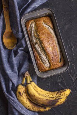 Geleneksel bir Amerikan yemeği, siyah beton arka planda glüten ve sütsüz muz ekmeğidir. Üst görünüm, alanı kopyala.