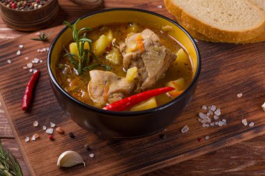 Ahşap bir masada haşlanmış patates ve tavuk etiyle kalın bir tabak.