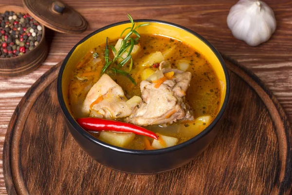 Ahşap bir masada haşlanmış patates ve tavuk etiyle kalın bir tabak.