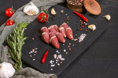 Kara tahtada taze çiğ tavuk kalbi, biber, tuz ve biberiye. Tavuk sakatatı