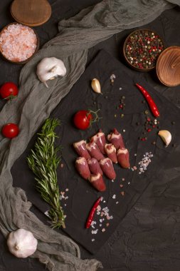 Kara tahtada taze çiğ tavuk kalbi, biber, tuz ve biberiye. Tavuk sakatatı.