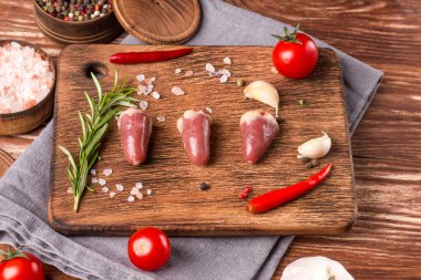 Tahtada taze çiğ tavuk kalbi, biber, tuz ve biberiye ile birlikte. Tavuk sakatatı.