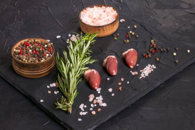 Kara tahtada taze çiğ tavuk kalbi, biber, tuz ve biberiye. Tavuk sakatatı.