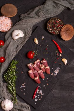 Kara tahtada taze çiğ tavuk kalbi, biber, tuz ve biberiye. Tavuk sakatatı.