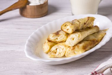 Süzme peynirli, üzümlü ve ekşi kremalı dürülmüş krep..