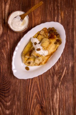 Süzme peynirli, kuru üzümlü, ahşap masadaki kremayla doldurulmuş ince krepler. Süper manzara.