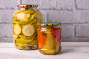 Gri bir duvara karşı ahşap arka planda kavanozlar dolusu sebze konservesi. Kış için ev yapımı sebzeler.