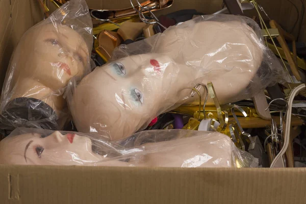 Paper box with female mannequin heads with makeup without hair in plastic bags and assorted hangers. Delivery of goods for purchases during the coronavirus. Shop of commercial equipment.