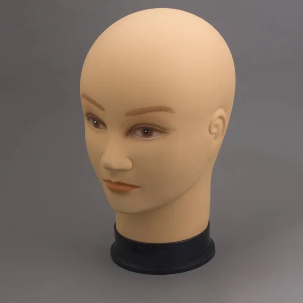 Mannequin full face of head of young white woman without hair on grey background. Shop concept, sale, design. Fashionable silicone mannequin made of durable material