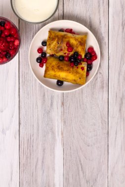 Süzme peynirle doldurulmuş ince krepler ve ahşap masada fotokopi alanı olan böğürtlenler