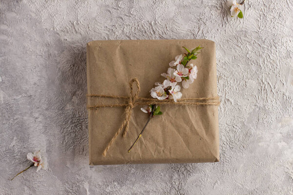 Подарочная коробка с веткой цветущей сакуры на светлом столе. Плоский лежал