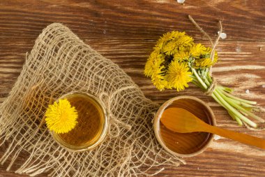 Sarı karahindiba ile birlikte açık ahşap bir masada ev yapımı lezzetli bir karahindiba balı. Karahindiba çiçeği şurubu. Kış için kullanışlı bir koruma