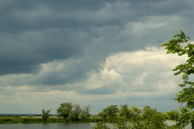 Gökyüzü yağmurdan önce bulutludur. Nehrin üstündeki gökyüzünde gri fırtına bulutları.