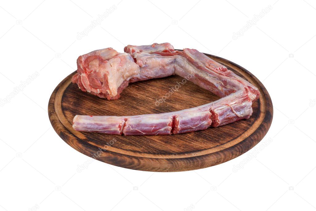 Whole fresh raw beef tail chopped into pieces on round wooden board isolated on white background.