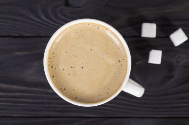 İşyeri modeli, bir bardak kapuçino ile ahşap, koyu bir masada, dizüstü bilgisayar ve not defteriyle..