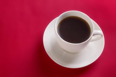 Kırmızı zemin üzerinde kırmızı bir fincan üzerinde sıcak aromatik kahve ve fotokopi alanı olan beyaz fincan.