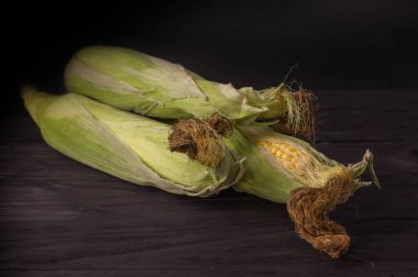 Siyah arka planda üç tane olgun mısır..