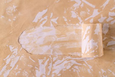 Yatay arkaplan ve kağıtta yırtık bir delik var. Kahve kağıdında bej rengi bir delik olan bir arka plan. Büyük buluş kağıdı.