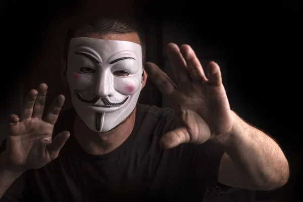 Anonymous with Guy Fawkes mask with raised hands.