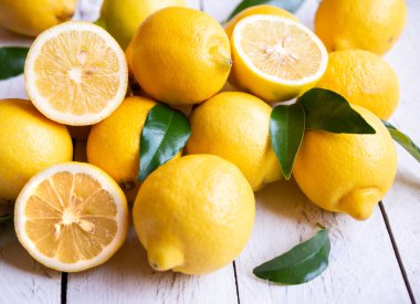 Taze ve olgun limonlar ve beyaz ahşap yapraklar.