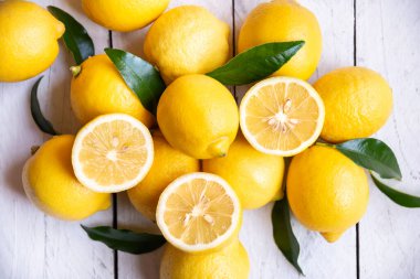 Taze ve olgun limonlar ve beyaz ahşap yapraklar.