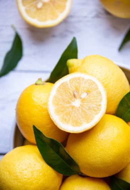 Taze ve olgun limonlar ve beyaz ahşap yapraklar.