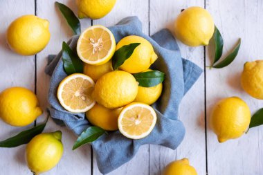 Taze ve olgun limonlar ve beyaz ahşap yapraklar.