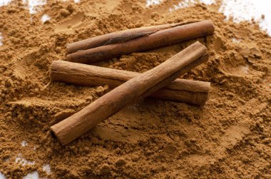 Kurutulmuş çiğ tarçın çubuklarını yakın plan olarak tozun üzerine koy.