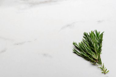 Beyaz mermer masada bir demet taze yeşil biberiye. Boş yer.