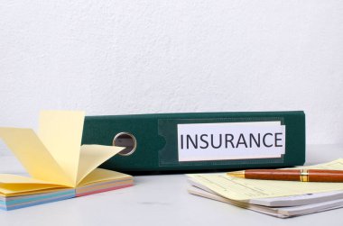 Sigorta belgeleri, kağıt çubukları ve diğer finansal belgelerle birlikte yeşil klasörün kapatılması.