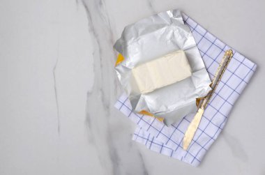 Mutfaktaki beyaz mermer masanın üzerindeki kareli peçetenin üzerindeki leziz tereyağı bloğunun en üst görüntüsü. Boş yer.