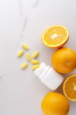 Dikey görüntü. C vitamini kapsülleri ve taze portakallar. Boş alan.