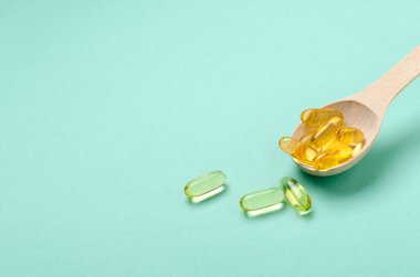 Mavi yüzeyde omega 3 vitaminlerle dolu tahta kaşık. Boş uzay.