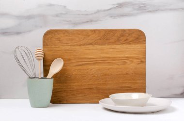 Boş ahşap mutfak tahtasına yakın çekim, çırpma ve ahşap hortum, bal kaplama, beyaz masadaki parlak tabaklar.