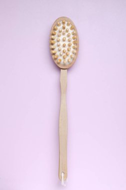 Dikey görüntü. Açık pembe yüzeyde kuru masaj için tahta fırça.