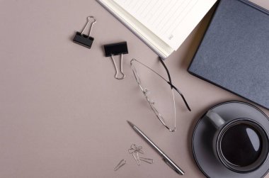 Kahve, kalem, cilt tokaları, not defterleri, bej masadaki bardaklar. Boş alan.