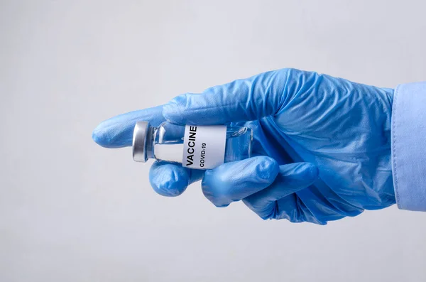 ワクチンのガラス瓶の閉鎖と灰色の背景に対する医師の手 予防接種の概念 — ストック写真