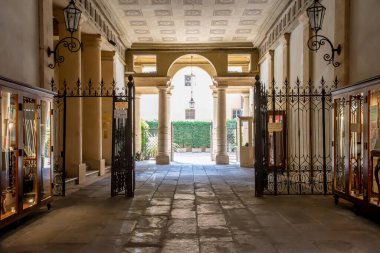 Verona, Veneto / İtalya - 18.08.2020: Bitki örtülü bir avluya doğru tarihi ve antik bir ev geçidine bakın. Kenarında sergilenen sergiler ve onları kapatacak bir şebeke görebilirsiniz..