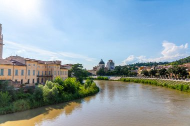 Verona, Veneto / İtalya - 18.08.2020: Verona 'daki Adige nehrinin bir kıvrımı kıyılarda evleri ve caddeleri olan tekneleri ve diğer navigasyonları olmadan güneşe karşı fotoğraflandı.