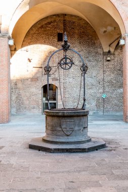 Bolonya, Emilia-Romagna / İtalya - 20.08.2020: Eski bir evin veya kalenin avlusunda vinç ve makaralı eski bir tarihi çeşme