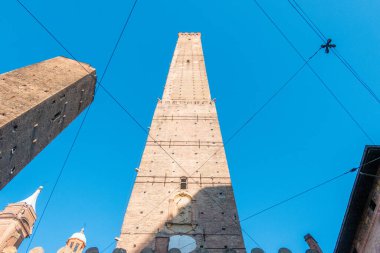 Bologna 'daki Torre Asinelli kulesi güneş ışığında ön planda kablolarla mavi gökyüzüne doğru fotoğraflandı.
