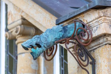 Metal bir heykel, muhtemelen verdigren ile kaplı bakır ve metal tellerle tutulmuş bir duvarda hayvan yüzü.