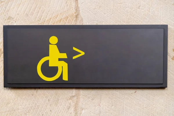 어두운 배경에 노란색 휠체어 표시와 오른쪽에 화살표가 벽에서 화장실 위치까지 — 스톡 사진