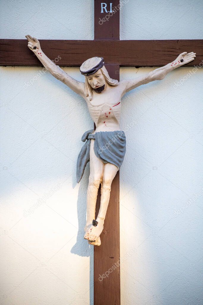 A brown wooden cross with a figure of Jesus crucified on a wall of a Christian house.
